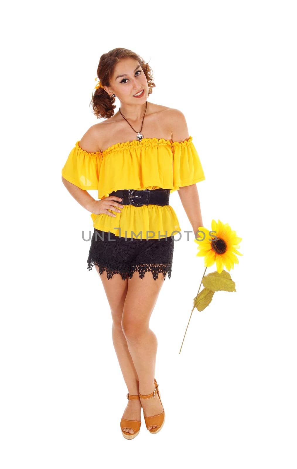 Gorgeous young woman in a yellow blouse and black shorts holding .one sunflower, standing isolated for white background..