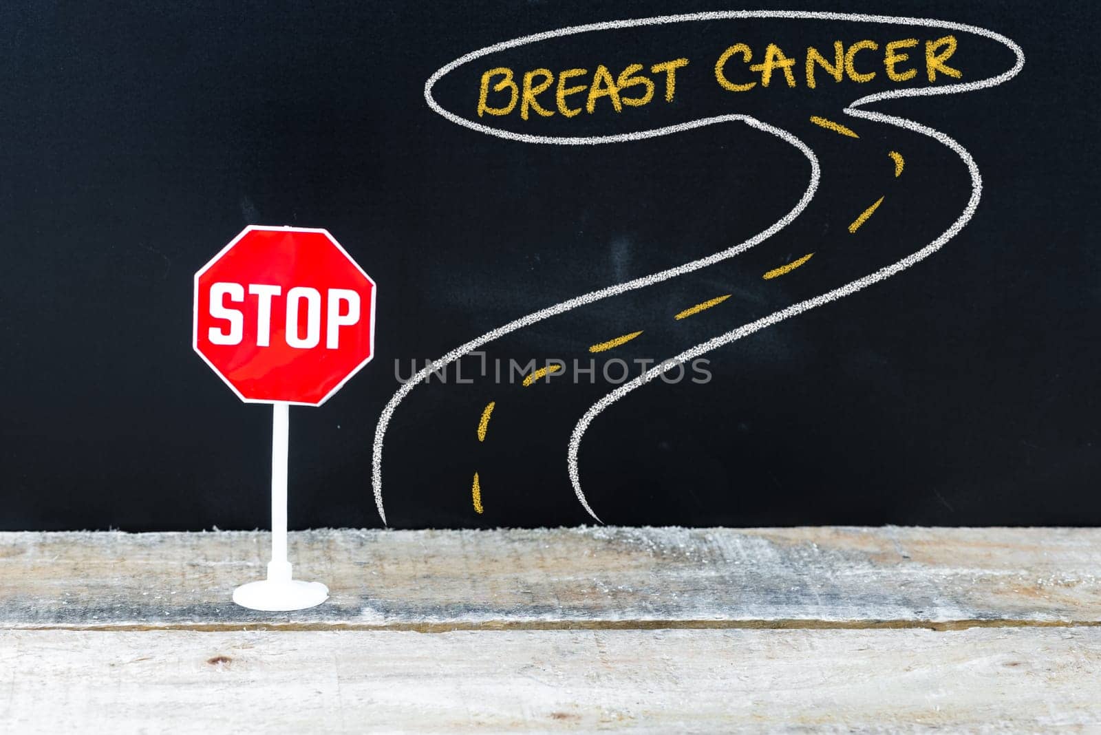 Mini STOP sign on the road to BREAST CANCER, hand drawing over chalkboard