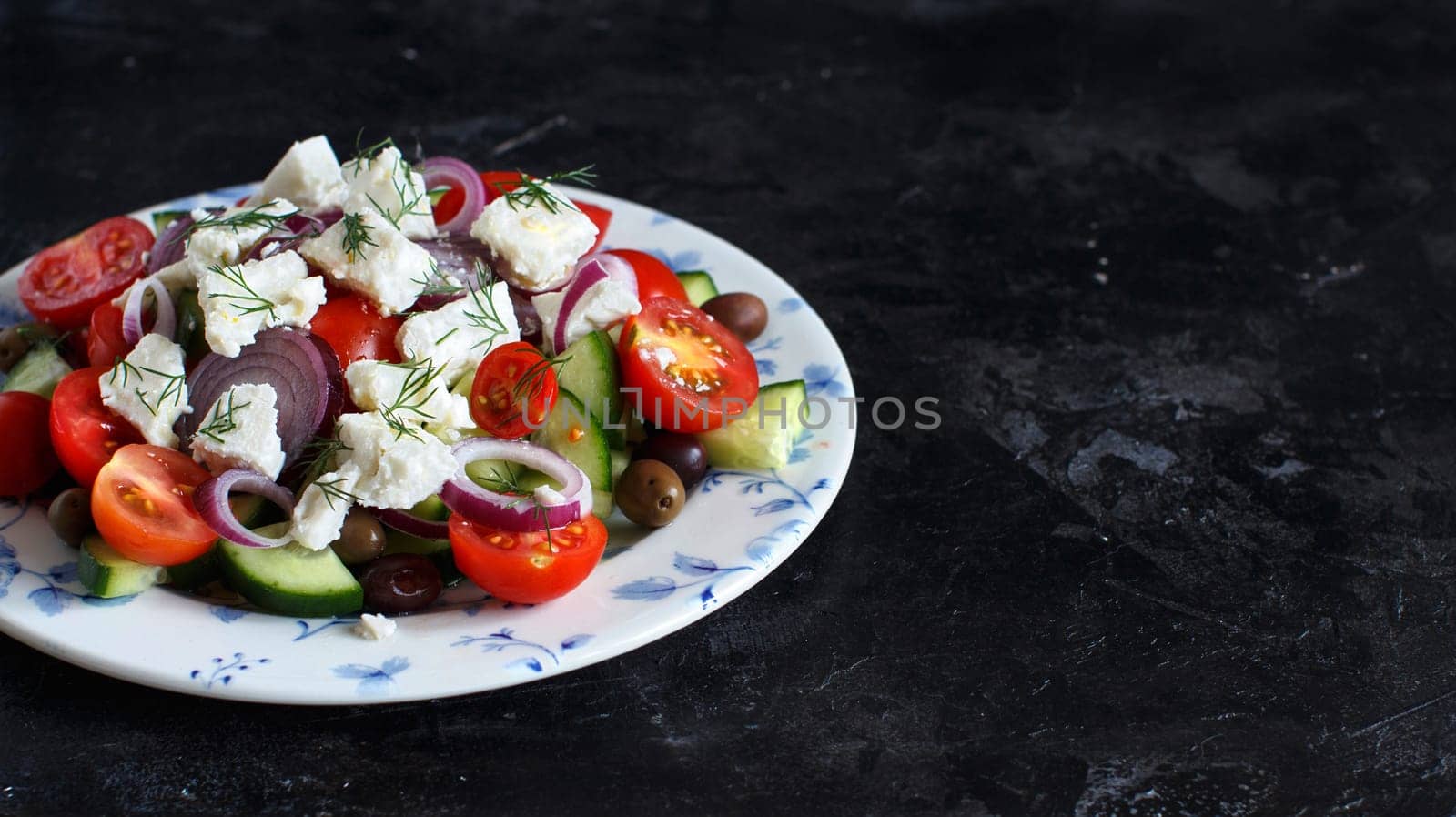 Greek salad with tomatoes, feta cheese, cucumbers, onions and olives