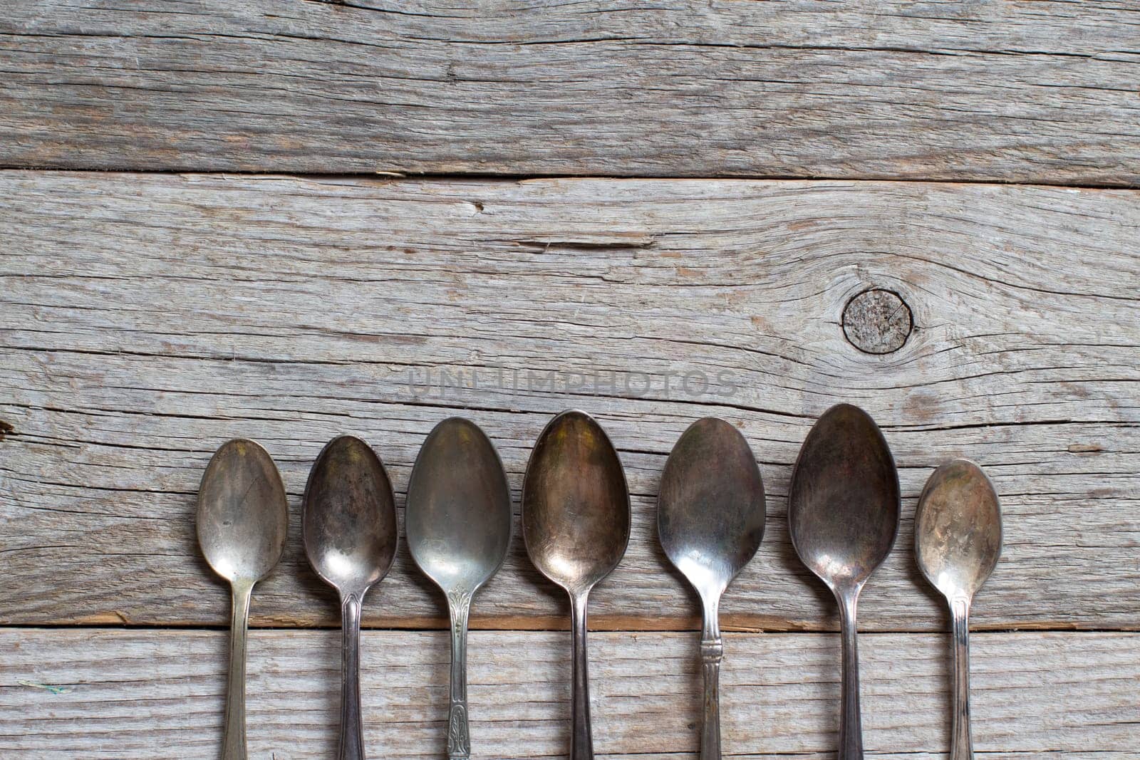 Vintage spoons with patina on old wooden table