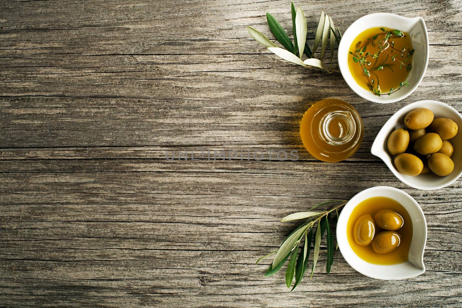 Olive oil with fresh herbs on wooden background