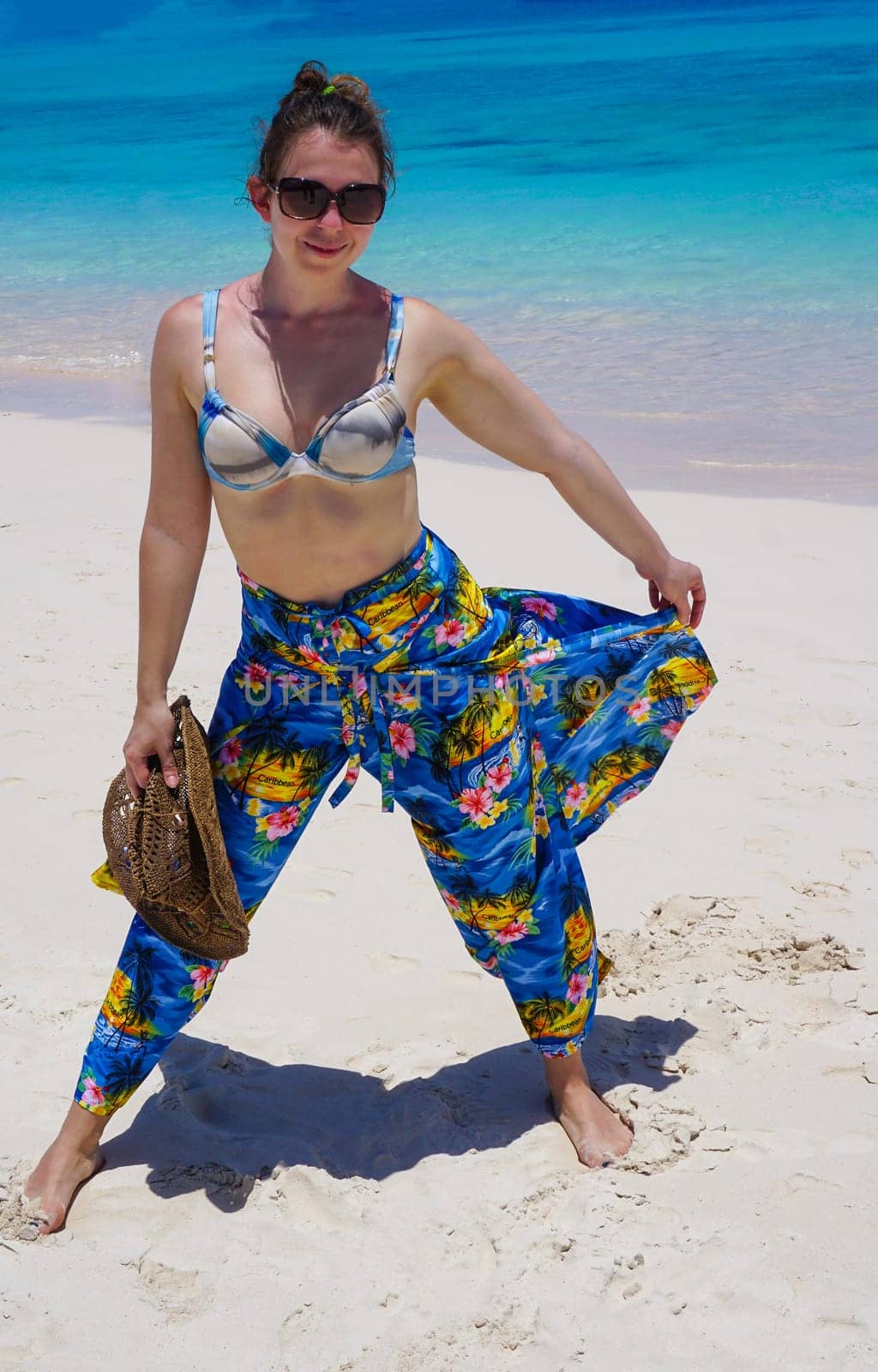 Beautiful woman on the beach with hat against the sand. Beautiful pants in the style caribbean
