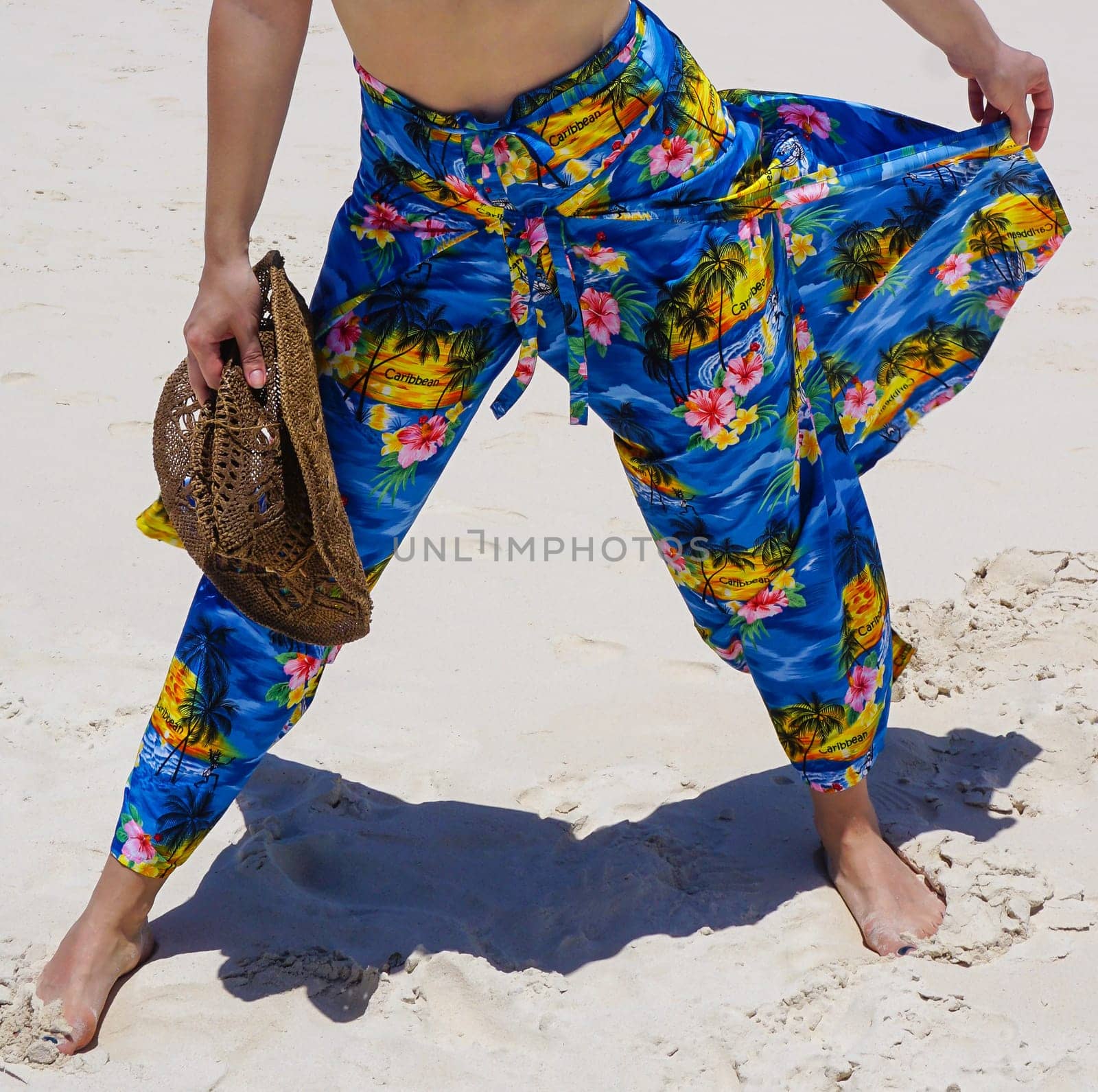 Beautiful woman on the beach with hat against the sand. Beautiful pants in the style caribbean