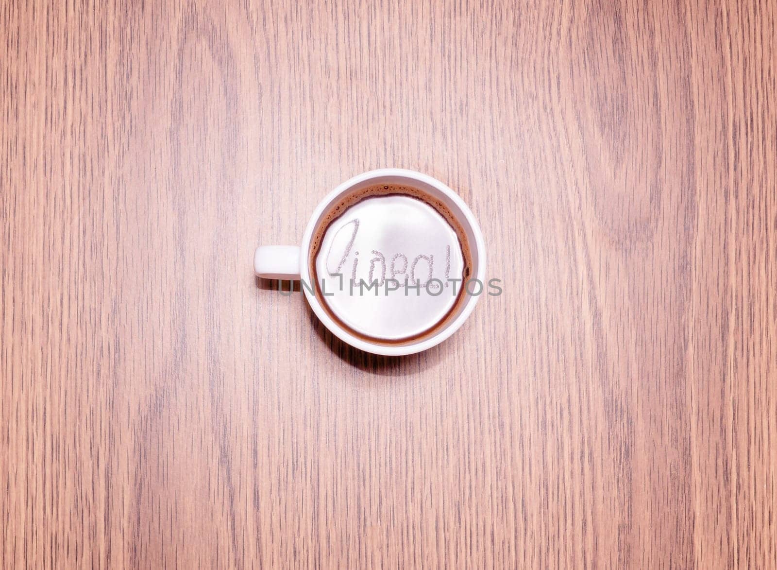 Inscription Idea and cup of coffee on wooden table