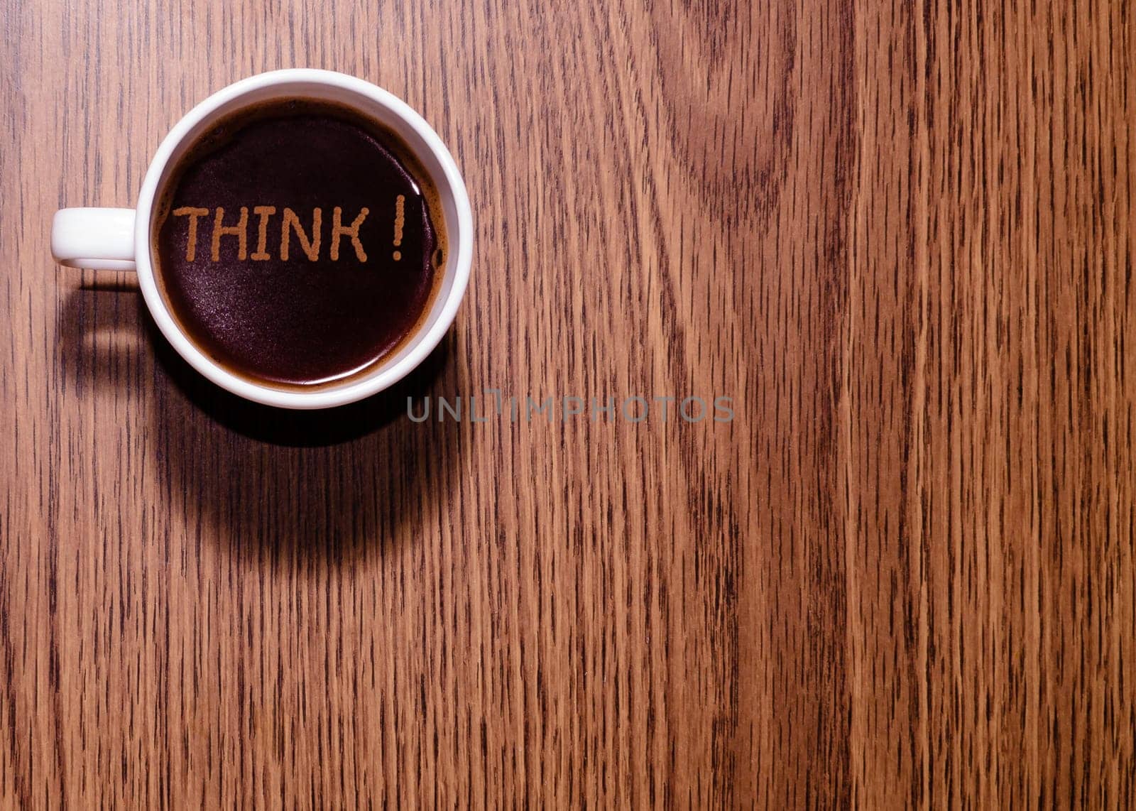 Inscription Think and cup of coffee on wooden table