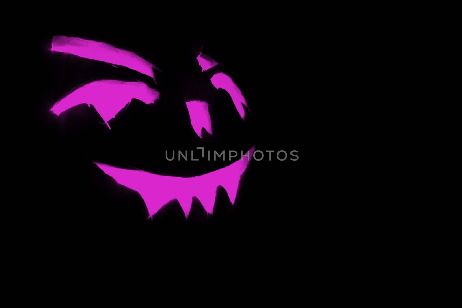 purple carved face of pumpkin glowing on halloween black background