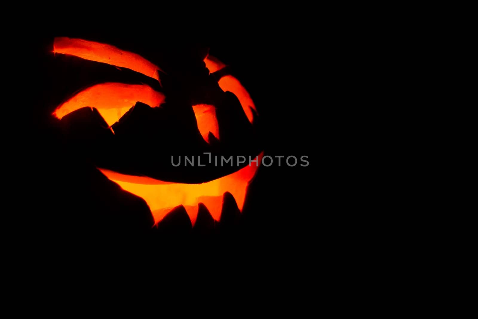 carved face of pumpkin glowing on halloween black background