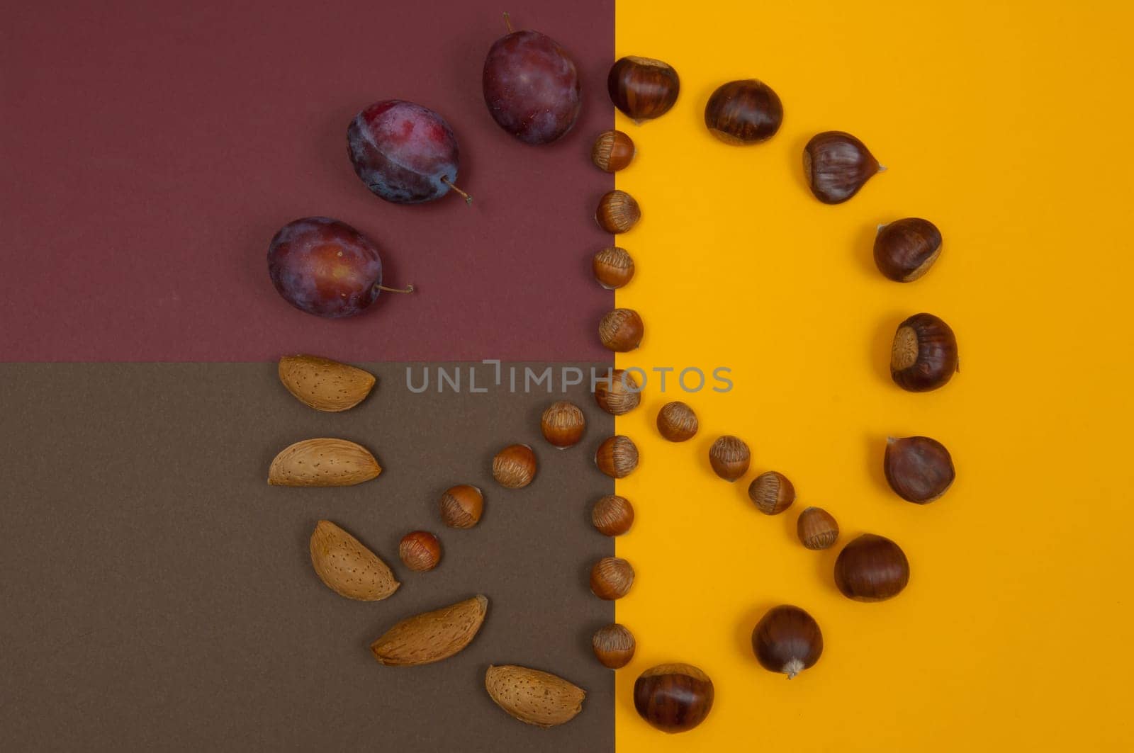 Peace symbol of in shell nuts and autumn fruits on split background