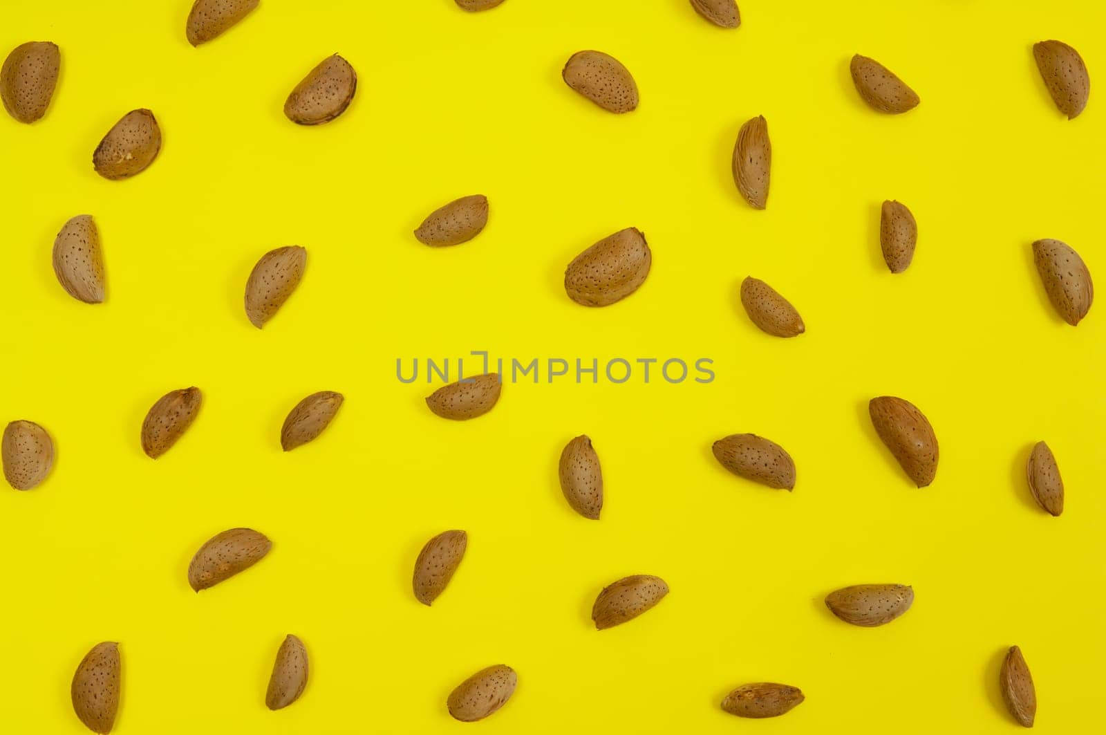 In shell raw almond on yellow background
