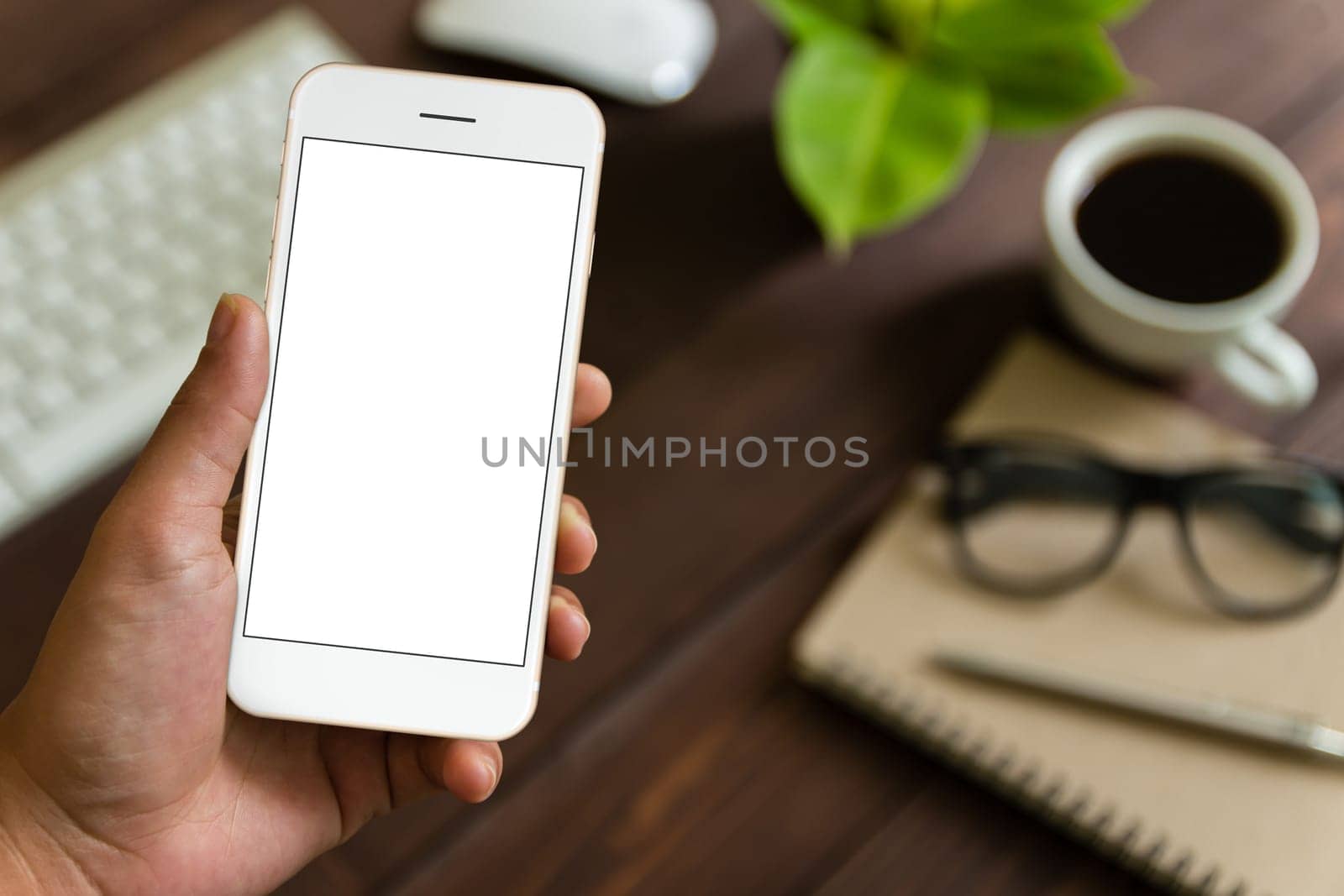 close up hand holding phone over work table, mockup phone blank screen for app screen adjustment