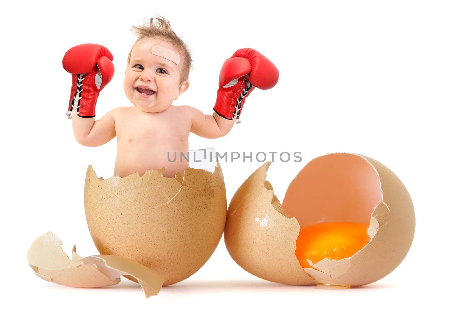 Beautiful baby boy with boxing gloves breaking the egg