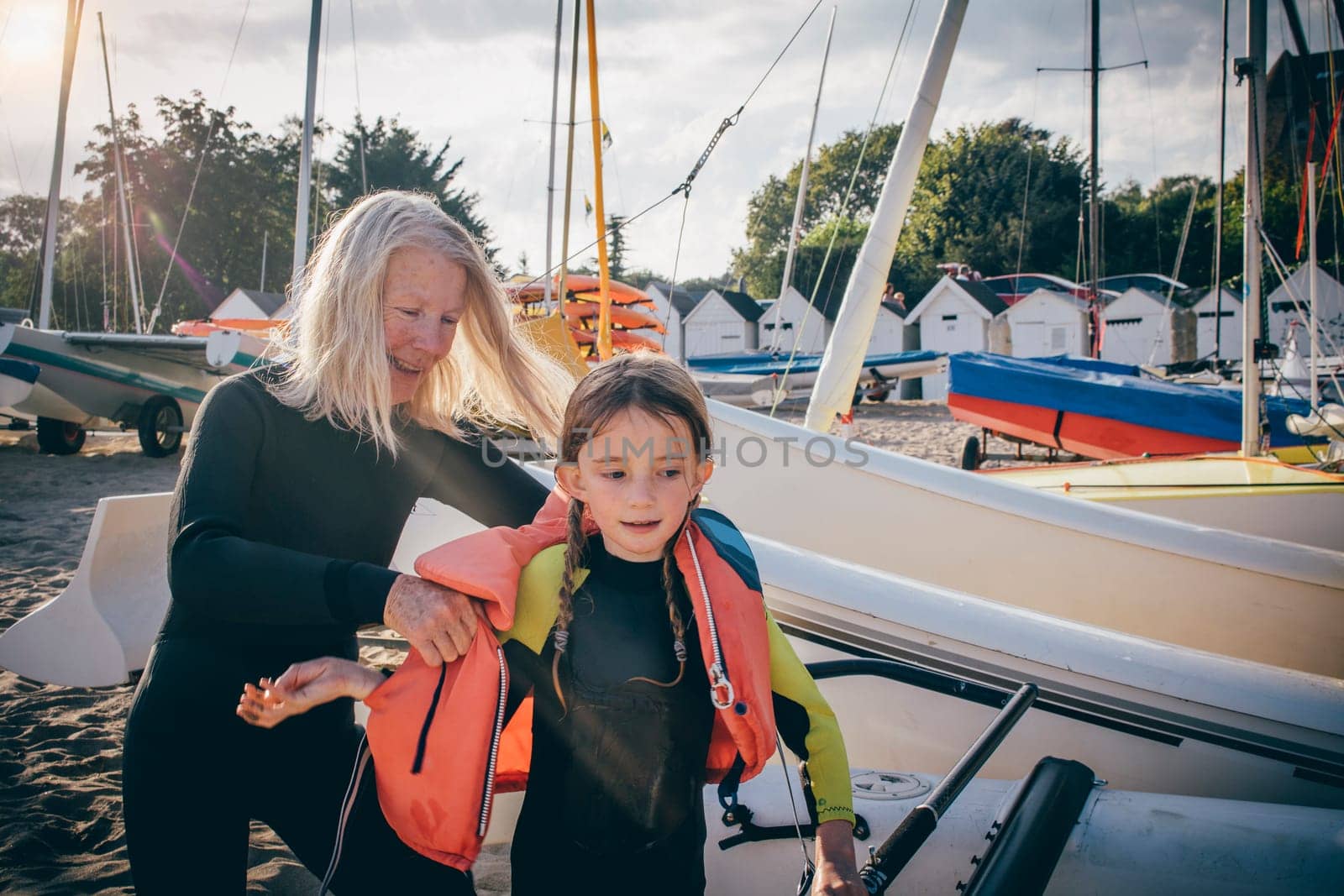 Little girl receiving a helping hand from her grandmother to get her lifejacket on.