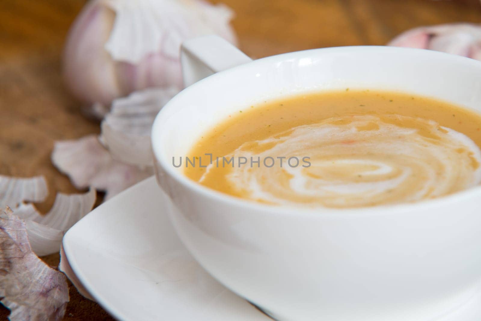 garlic cream soup in orange bowl on wooden background. rustic country style.