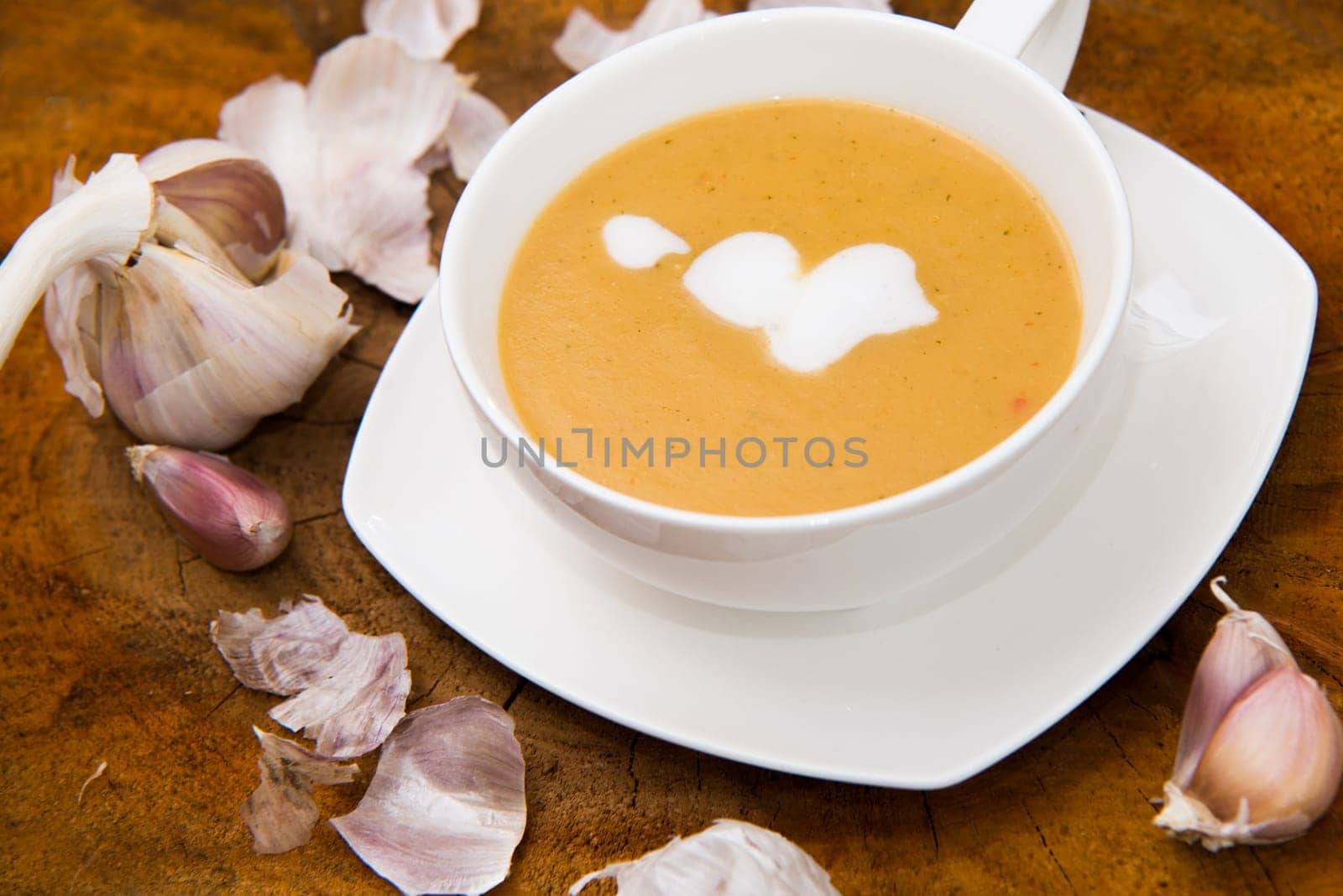 garlic cream soup in orange bowl on wooden background. rustic country style.