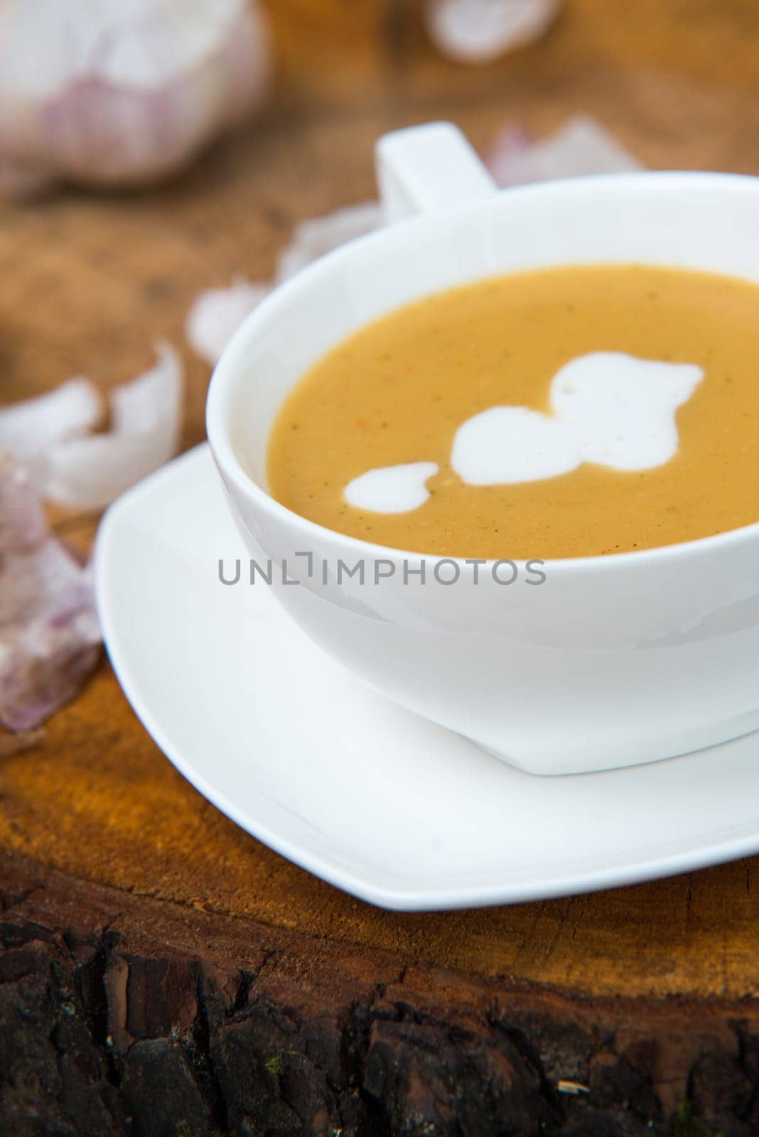 garlic cream soup in orange bowl on wooden background. rustic country style.