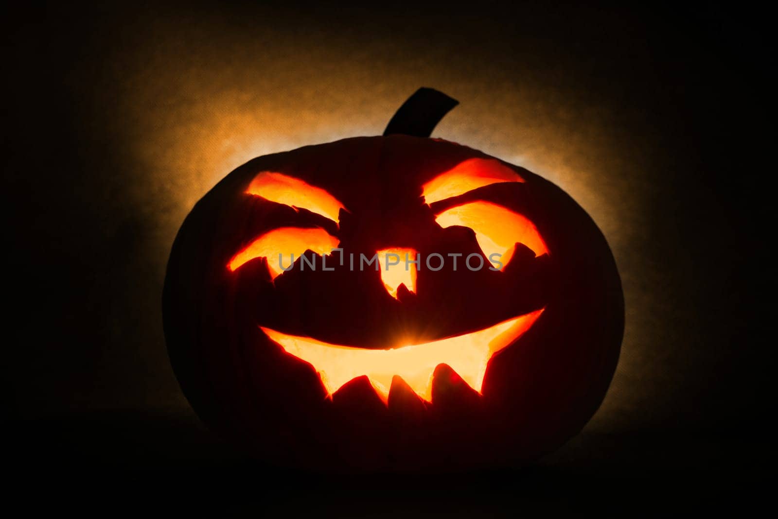 halloween pumpkin head jack lantern with burning candles on orange background