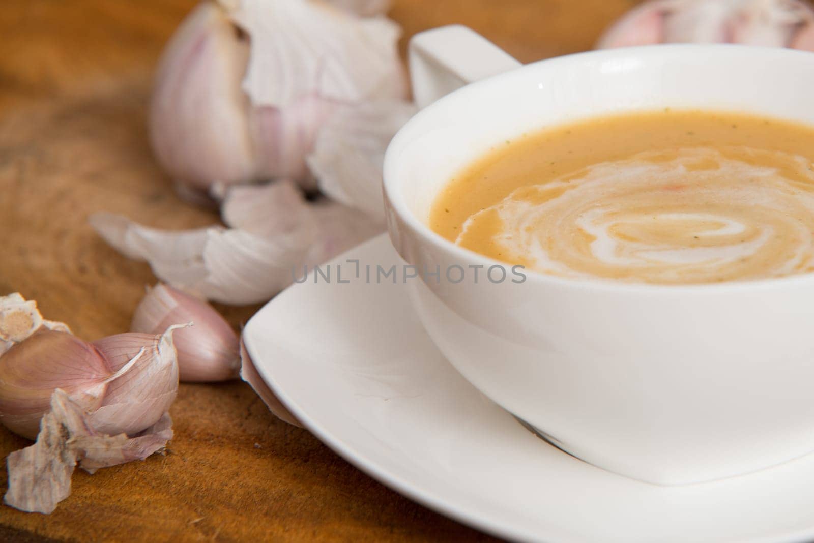 garlic cream soup in orange bowl on wooden background. rustic country style.