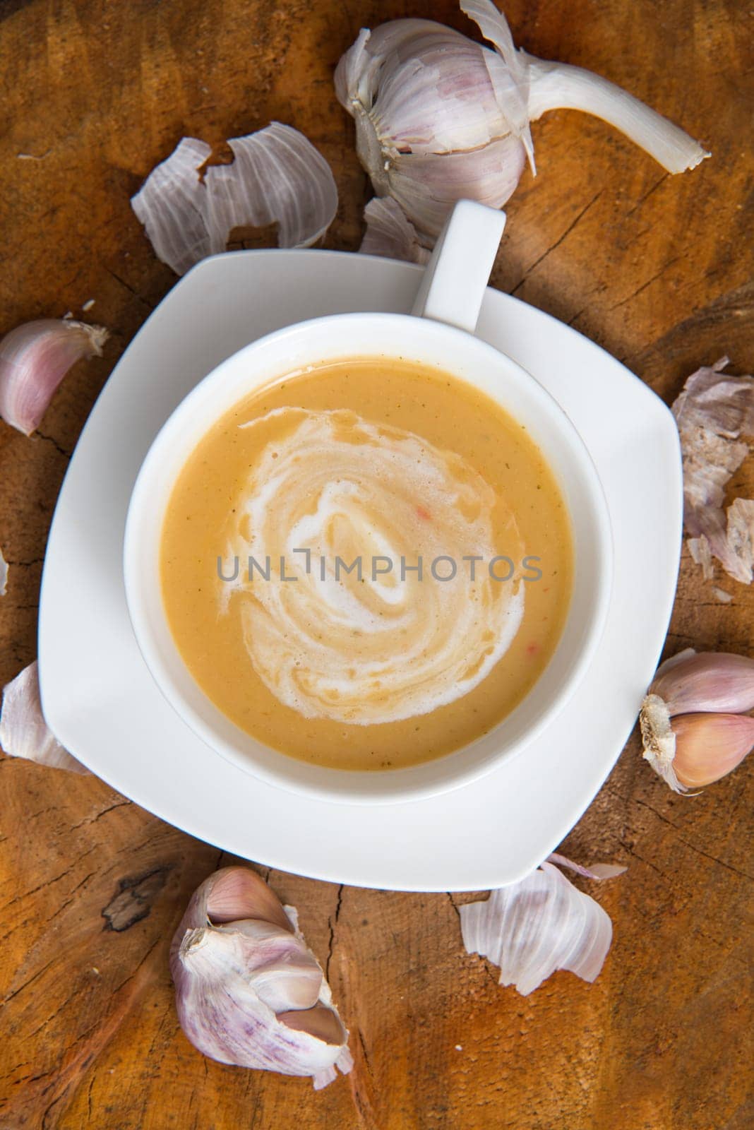garlic cream soup in orange bowl on wooden background. rustic country style. top view