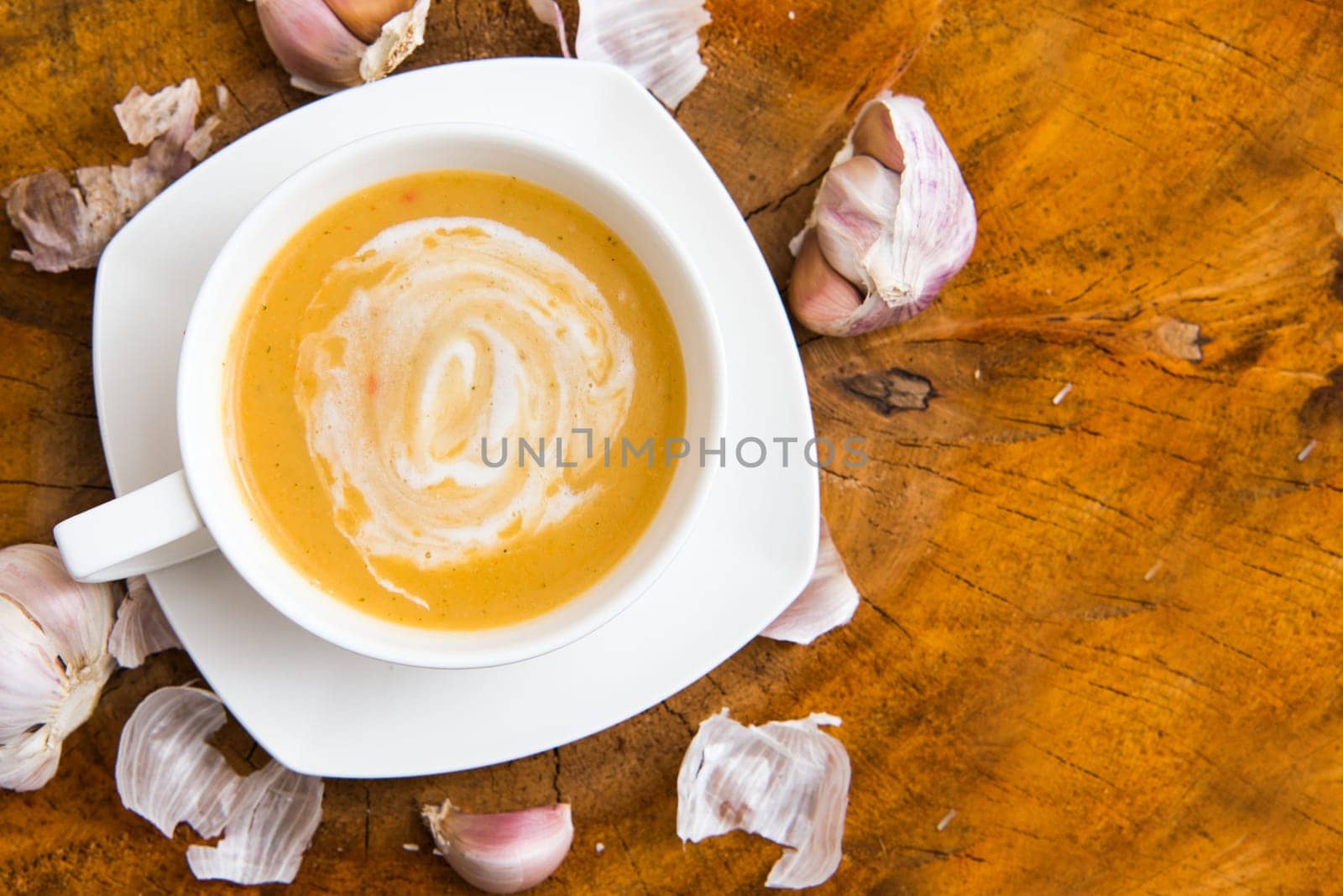 garlic cream soup in orange bowl on wooden background. rustic country style. top view