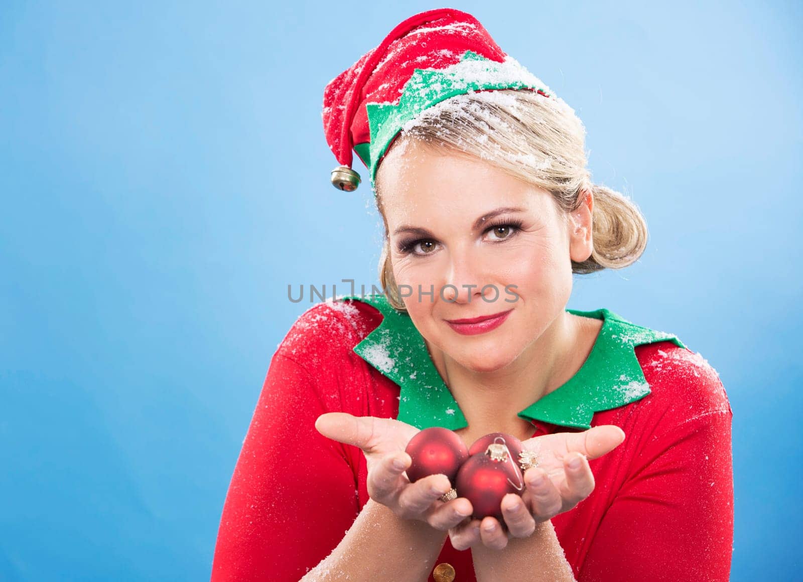 blonde woman wearing elf christmas costume on blue background