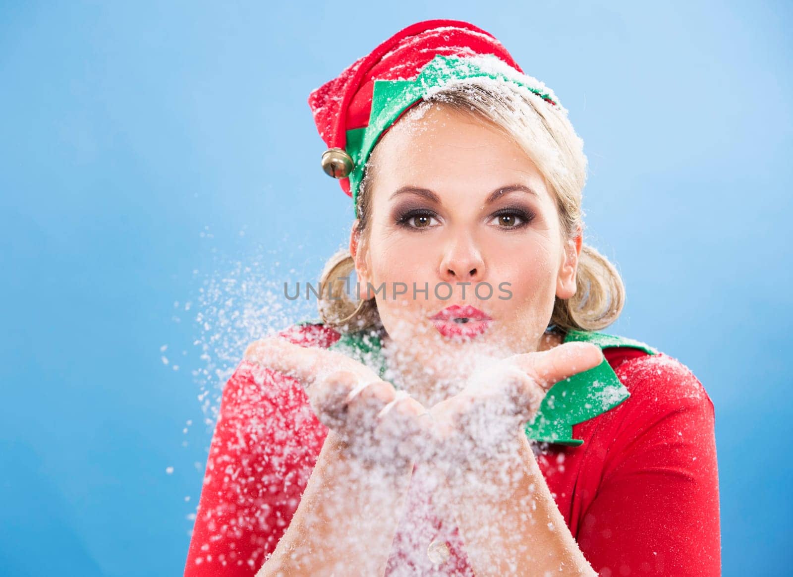 blonde woman wearing elf christmas costume on blue background