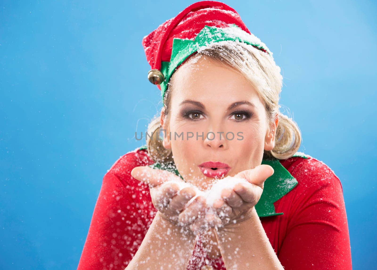 blonde woman wearing elf christmas costume on blue background