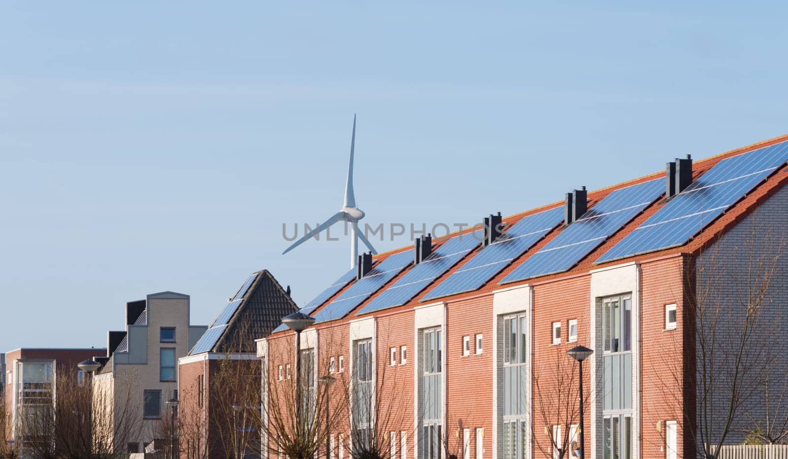 terraced houses with solar panels in front of a large windmill