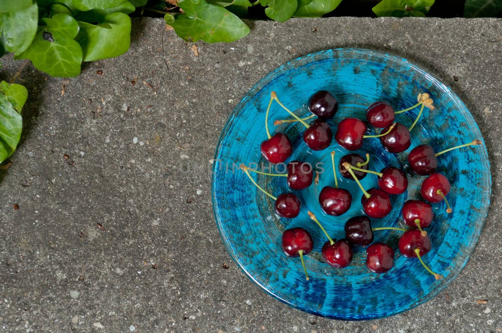 Delicious ripe cherry  on blue plate on grey stone flat lay Healthy fruit eating Top view