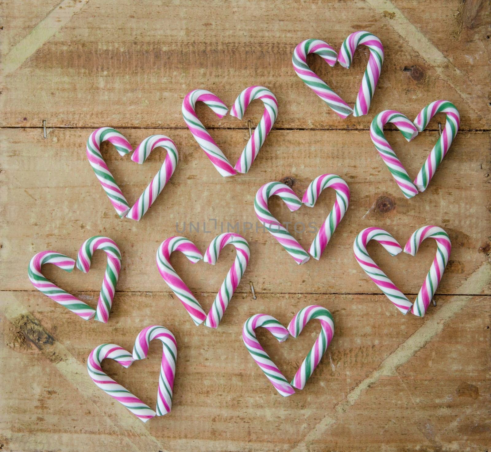 Small colorful candy canes on a rustic wooden background