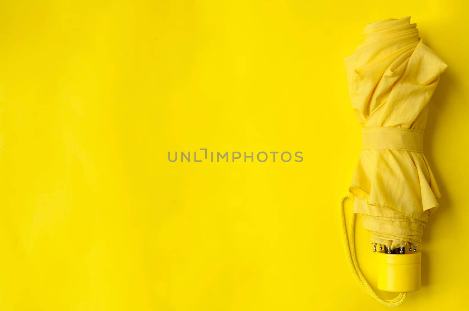 Umbrella on the right side of a yellow background, folded umbrella