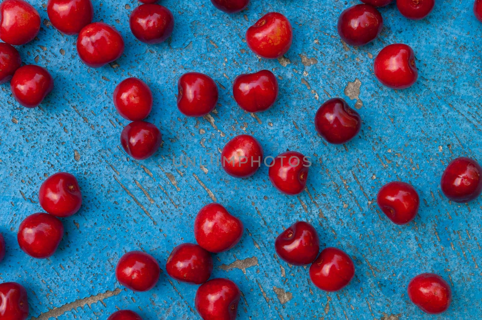 Arrangement of ripe cherries on blue textrured background, cherry pattern