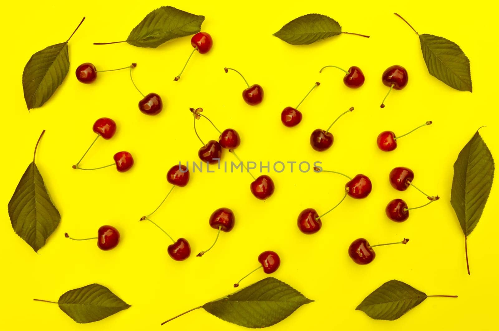 Cherry, cherries with cherry leaves on yellow background, top view