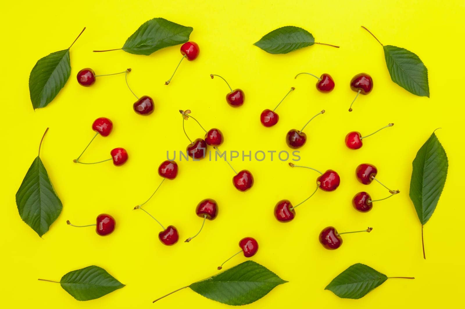Cherry, cherries with cherry leaves on yellow background, top view