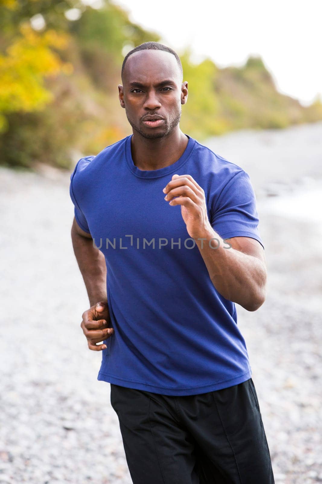 young black man wearing athletic wear running on the beach