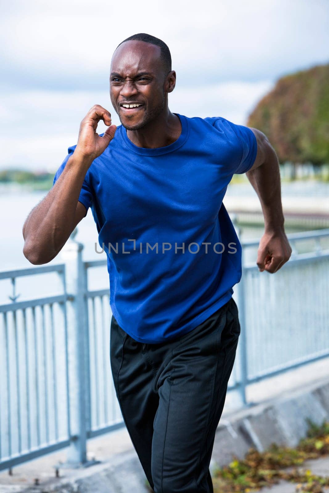 young black man wearing athletic wear running around the lake
