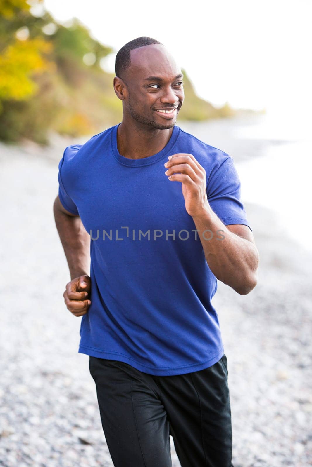 young black man wearing athletic wear running on the beach