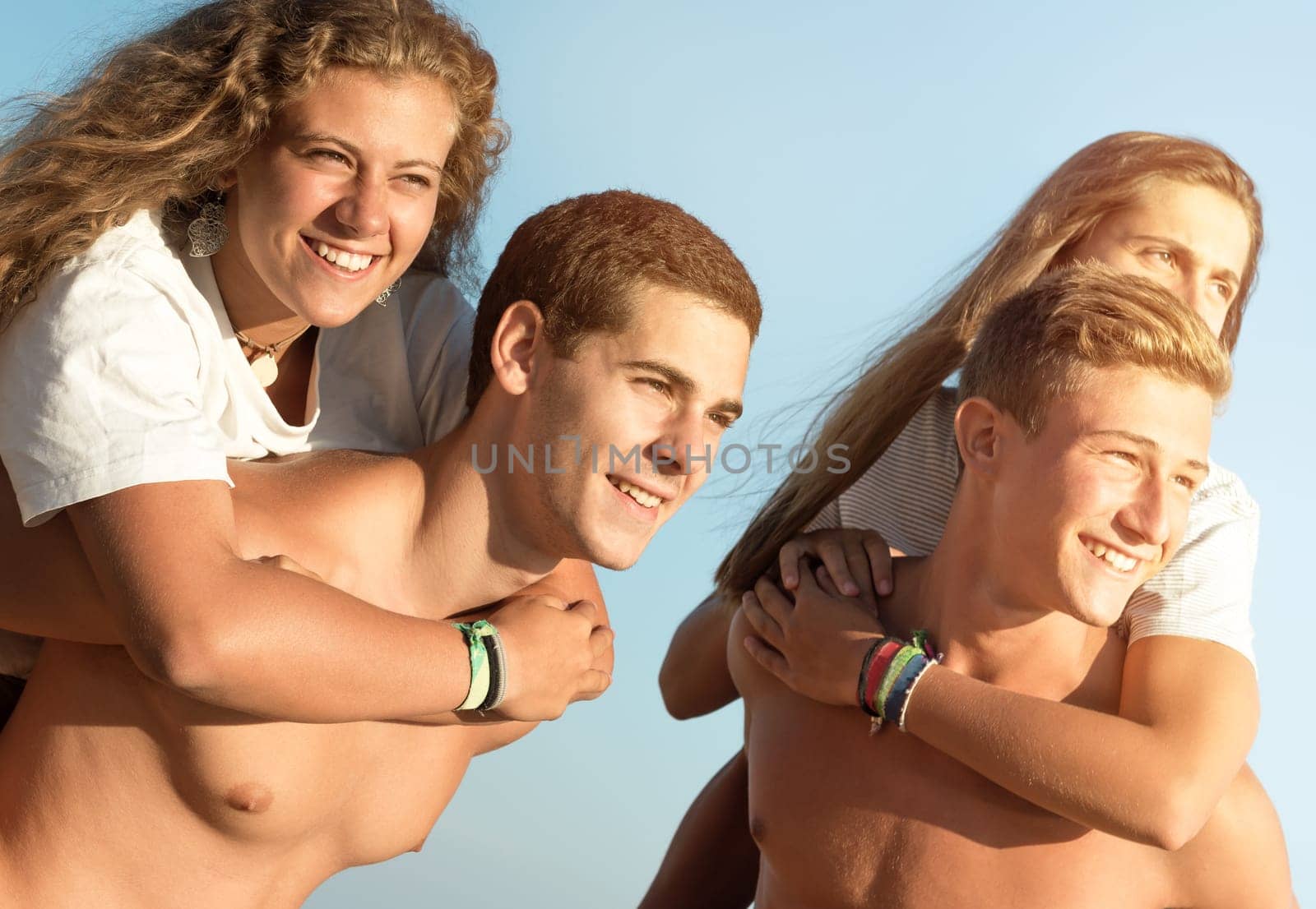 Happy teenage couples playing at the beach