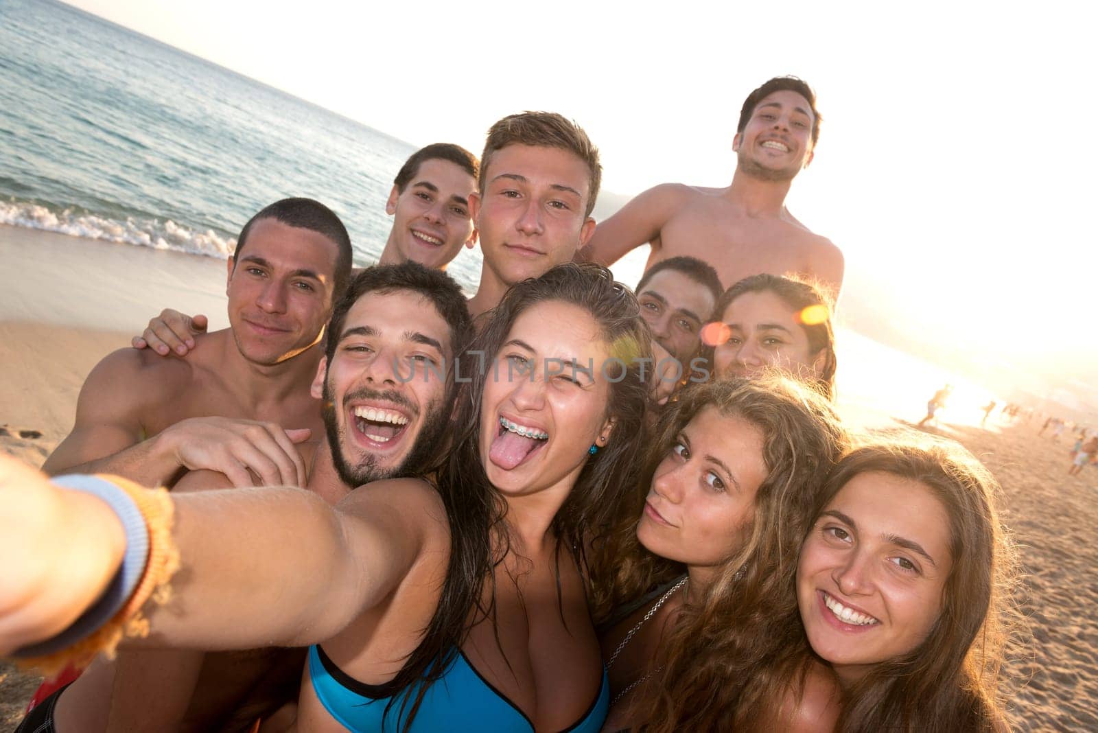 Group of happy teenage friends taking a selfie in the beach