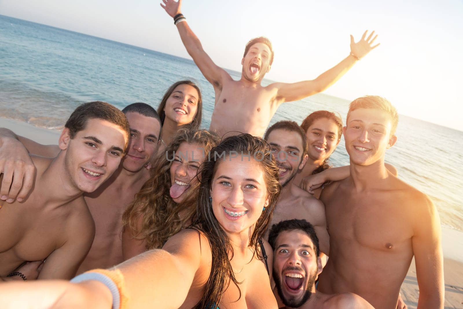 Group of happy teenage friends taking a selfie in the beach