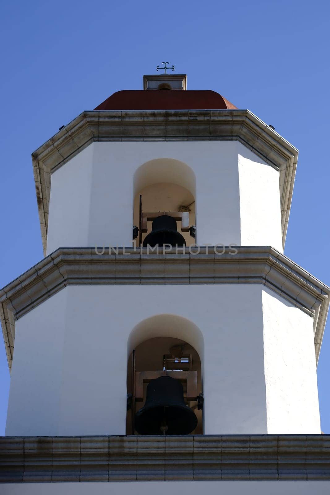 A bell tower of the Mission Basilica of San Juan Capistrano with several bells on top of each other.