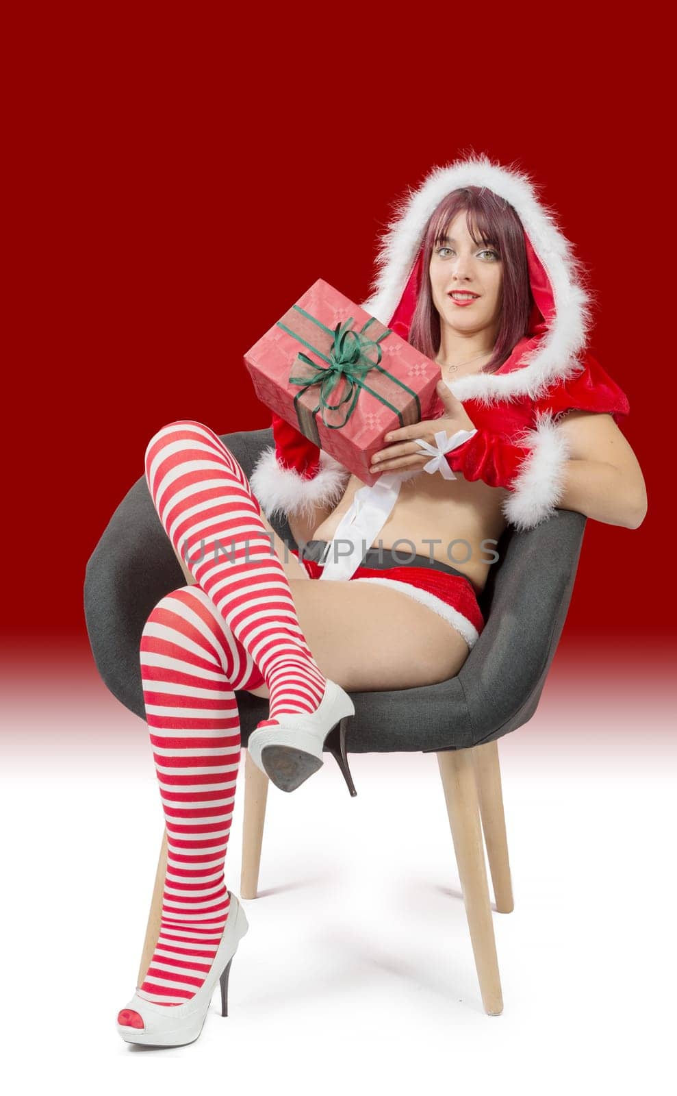 beautiful sexy girl wearing santa claus clothes sitting on armchair