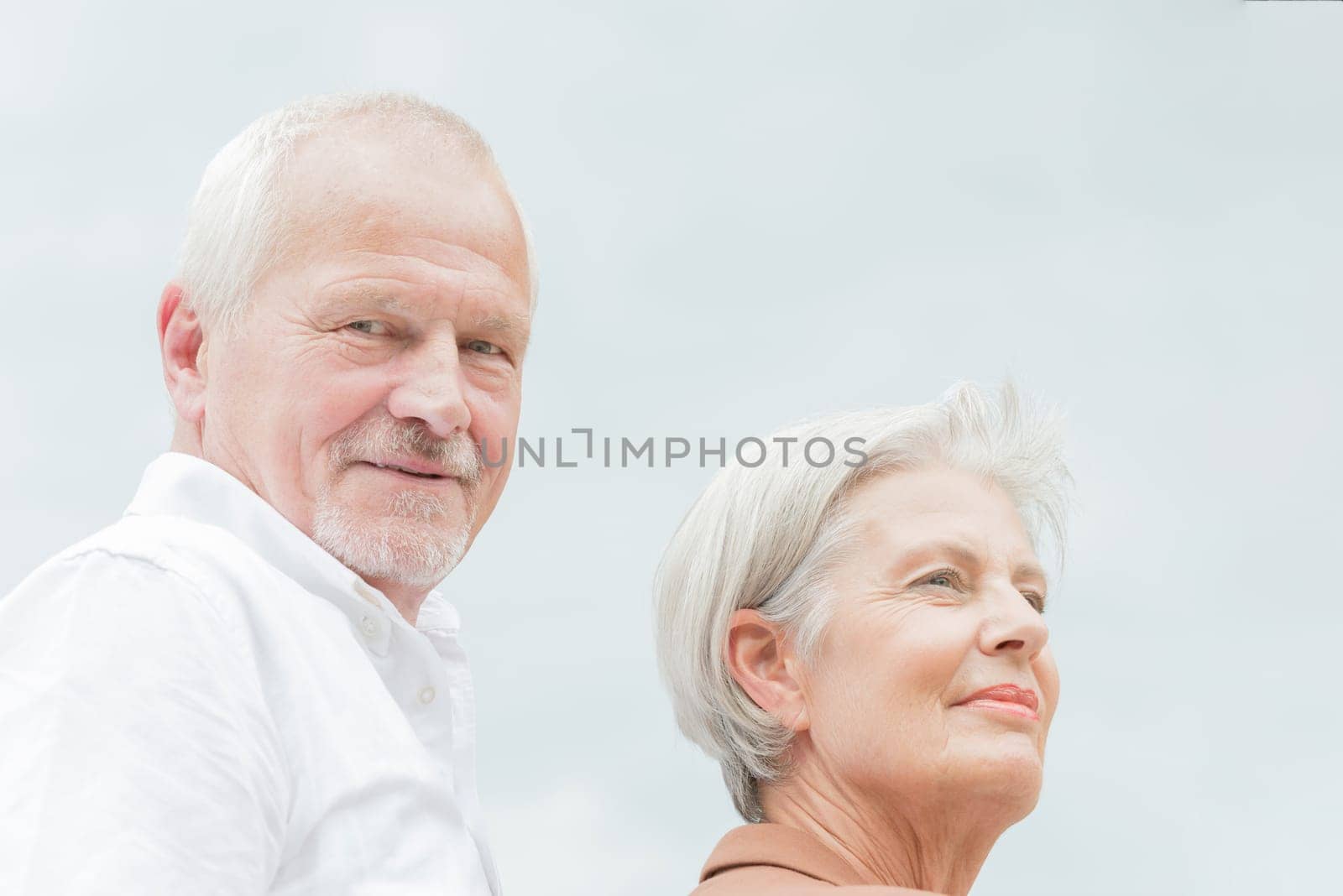 Active and happy senior couple in front of a bright sky