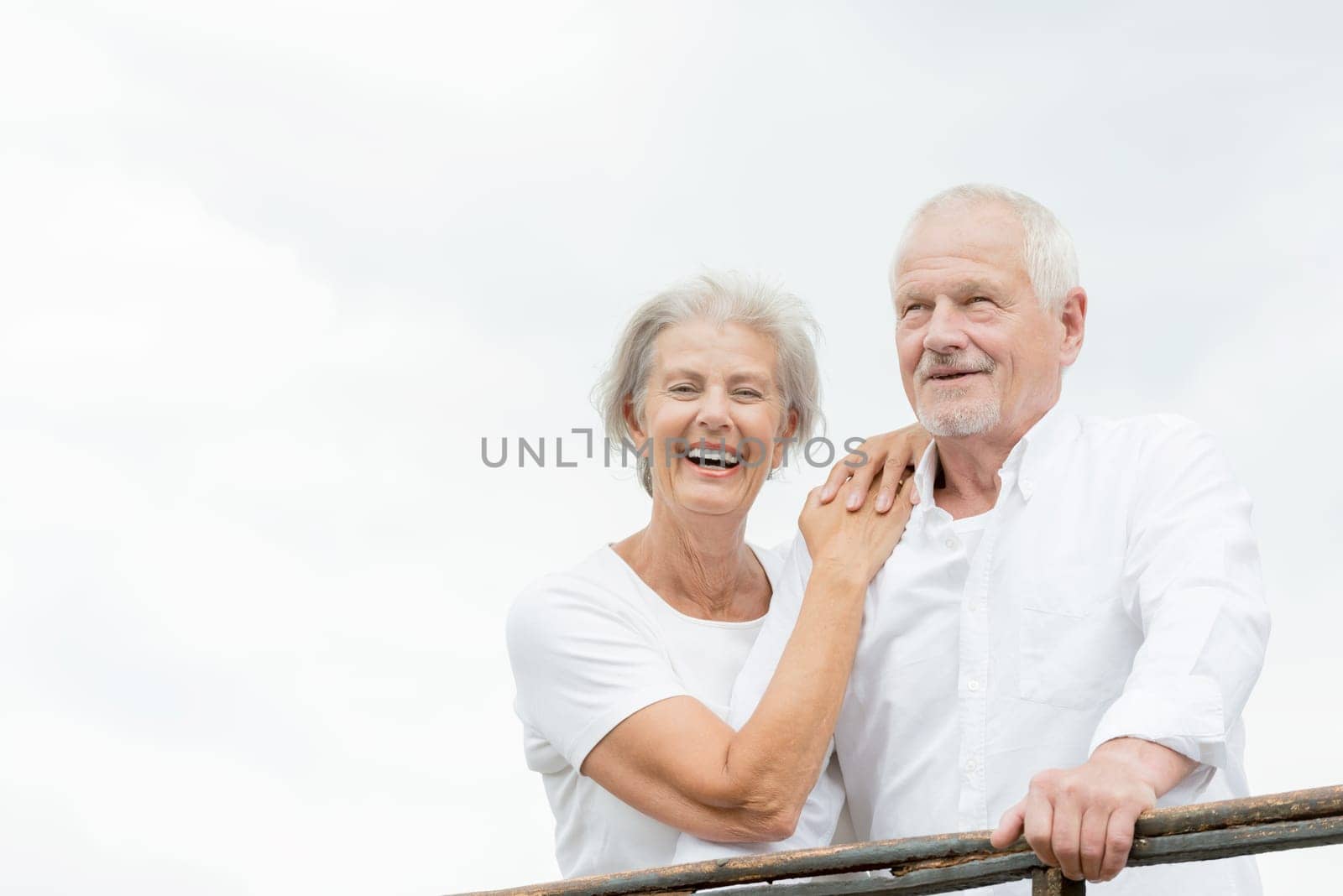 Active and happy senior couple in front of a bright sky