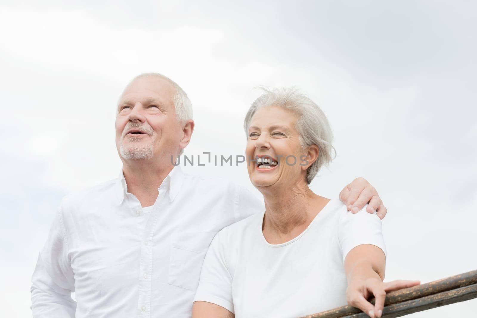 Active and happy senior couple in front of a bright sky