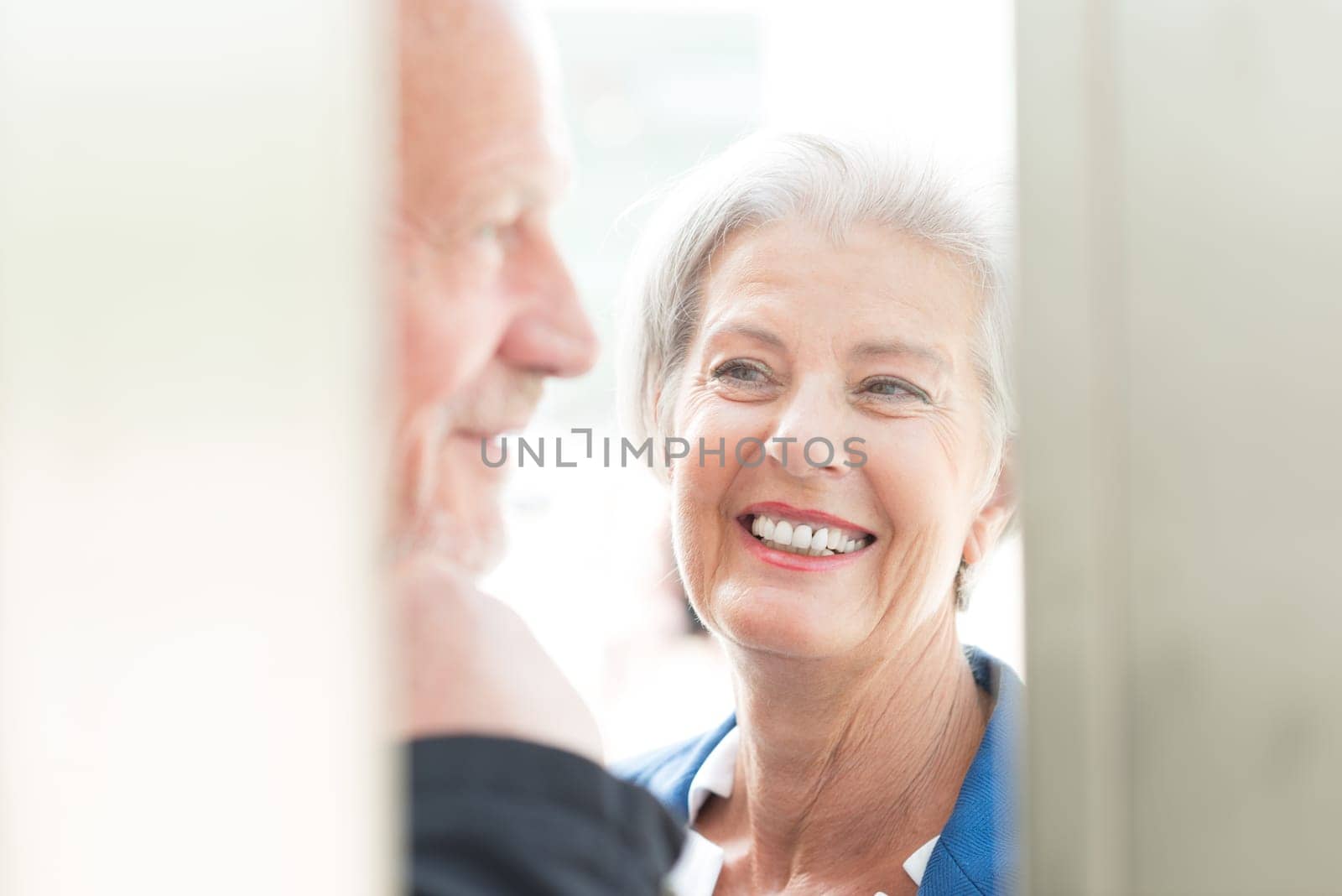 Two seniors stand at a public telephone booth and make phone calls