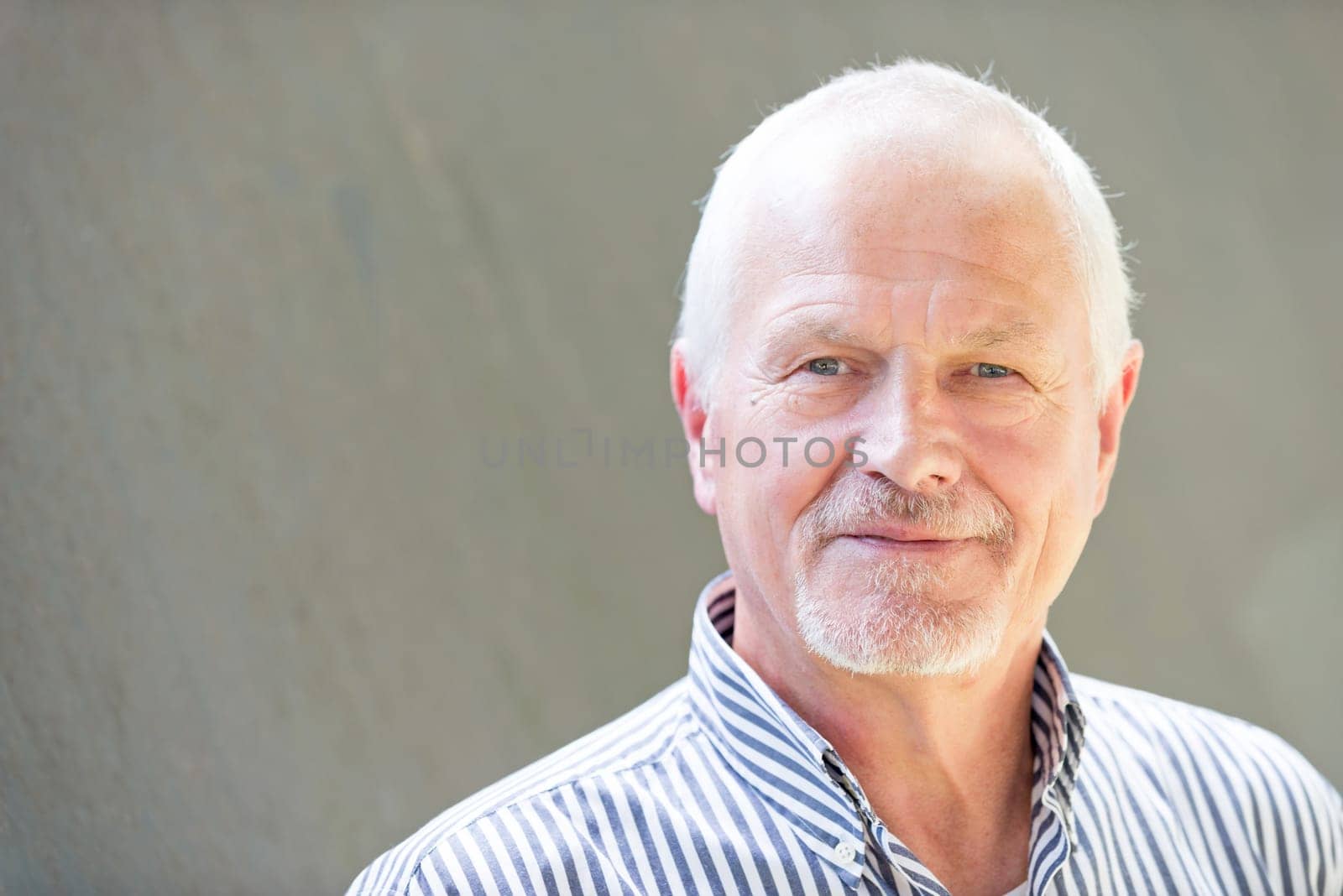 Portrait of a senior citizen against a grey background
