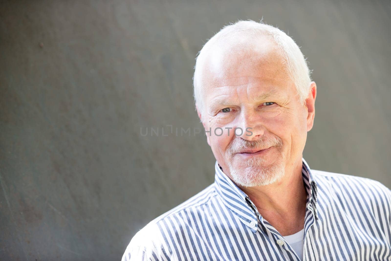 Portrait of a senior citizen against a grey background