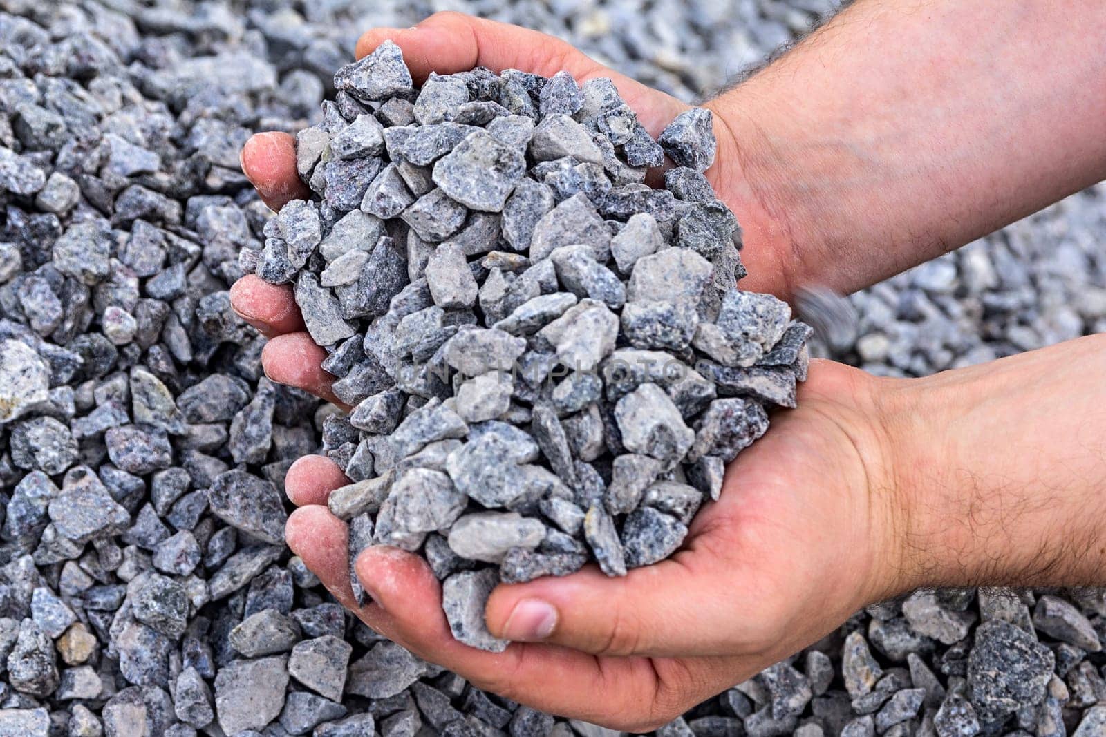 strong male hands holding a palm full of crushed granite