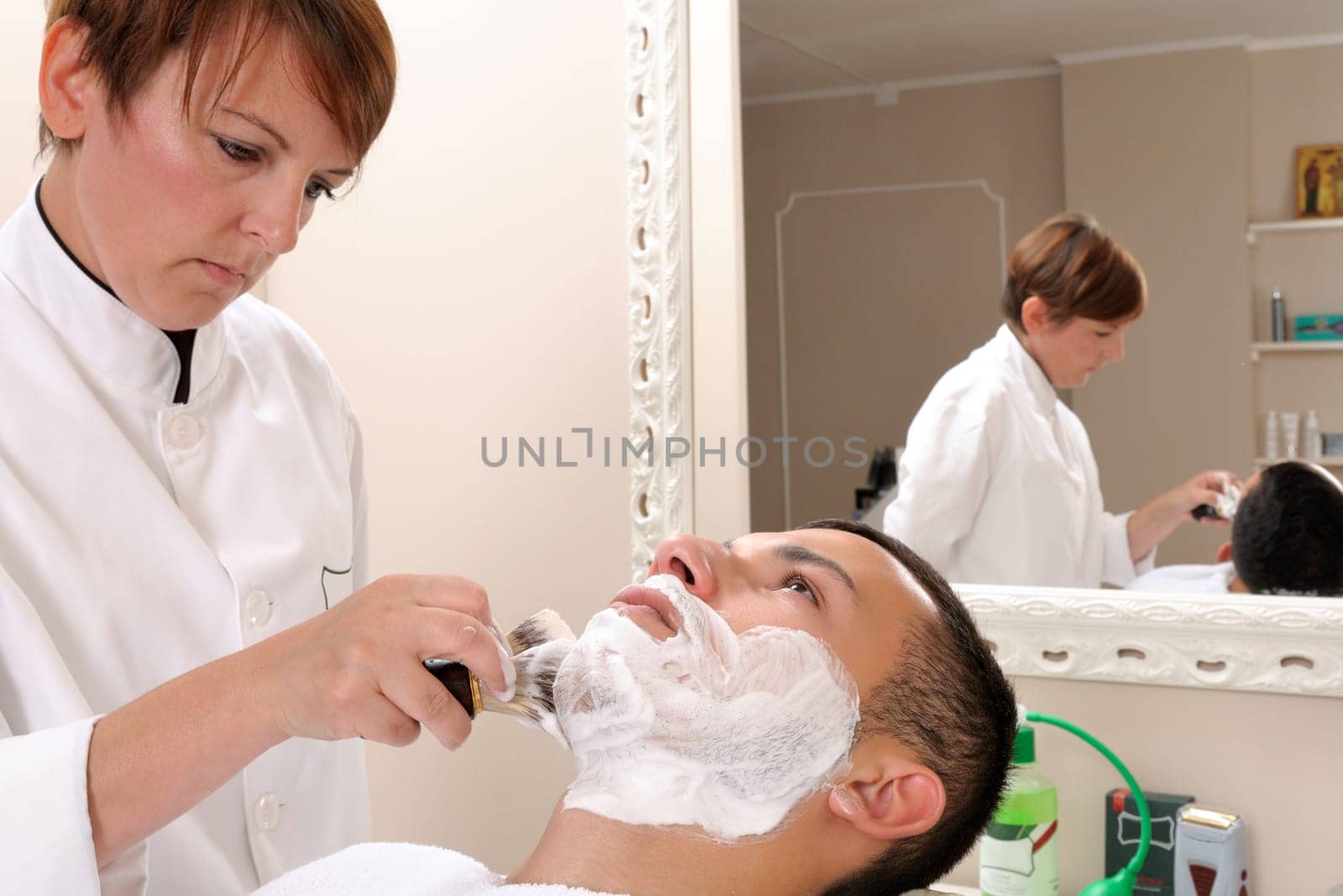 Shaving at the barber of a young boy in retro style with razor and shaving soap