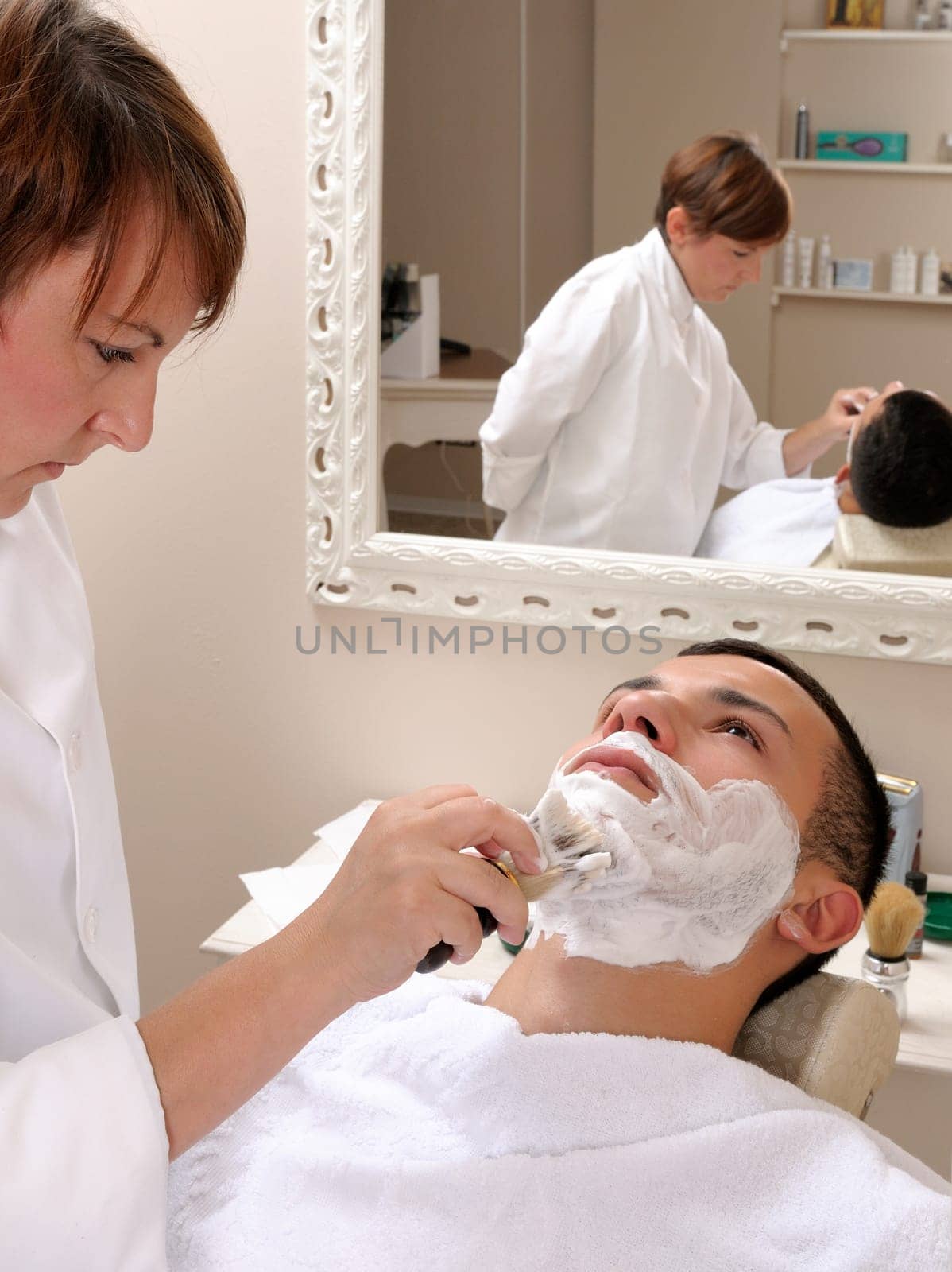 Shaving at the barber of a young boy in retro style with razor and shaving soap